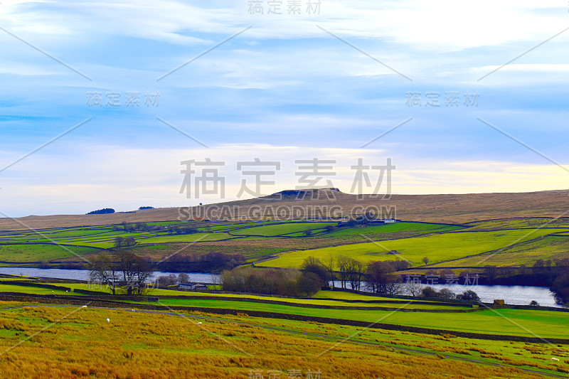 约克郡山谷的风景，绿色的田野上的山顶，干燥的石墙，树木映衬着阴沉的天空