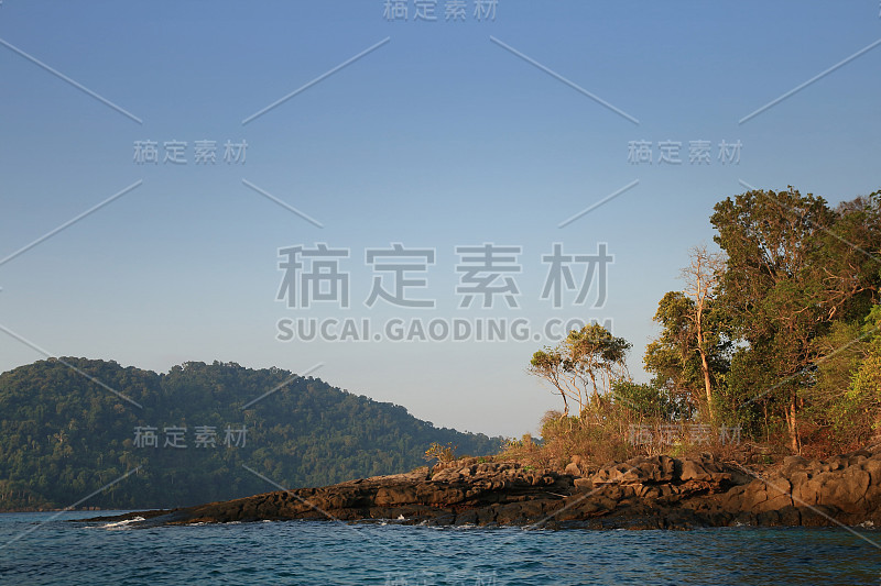 岩岸伸入海中。柔和的晨光，温暖的海景。在海洋中倾斜的陆地角的一角。梦想的度假目的地泰国。