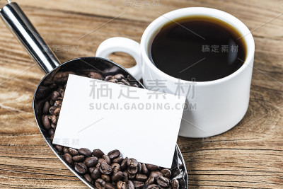 木桌上放着空白的名片和一杯咖啡。企业文具品牌模拟。