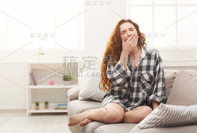年轻女子在米色沙发上打哈欠
