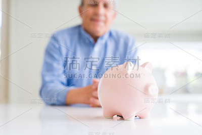 特写的小猪银行和男人微笑在背景