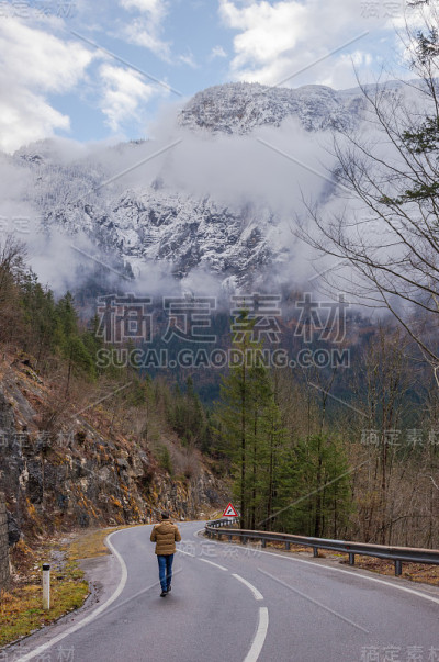 奥地利斯蒂里亚地区，一名男子走在美丽的山景路上