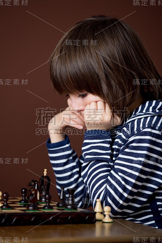 小男孩在下棋。聪明的孩子，孤立的，下棋。孩子玩智力游戏