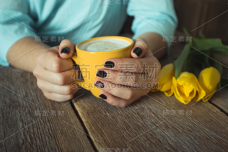 女人手中的黄杯。凝胶指甲修指甲