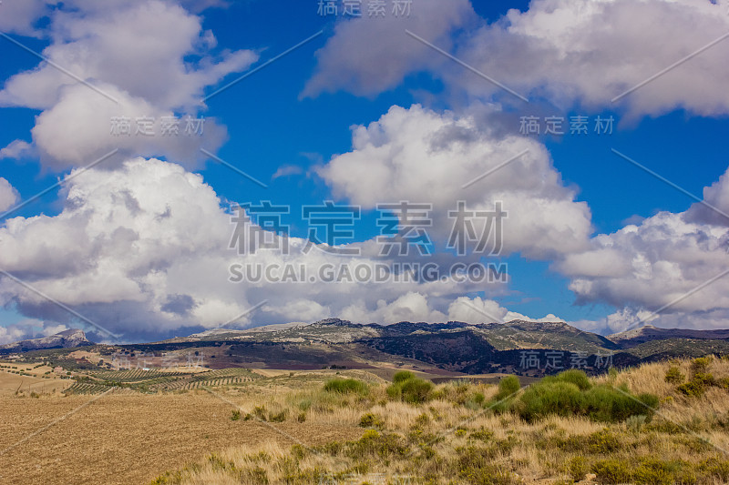 山景上的蓝色多云的天空背景。风景如画的群山在阳光下闪闪发光。令人屏息的自然影像