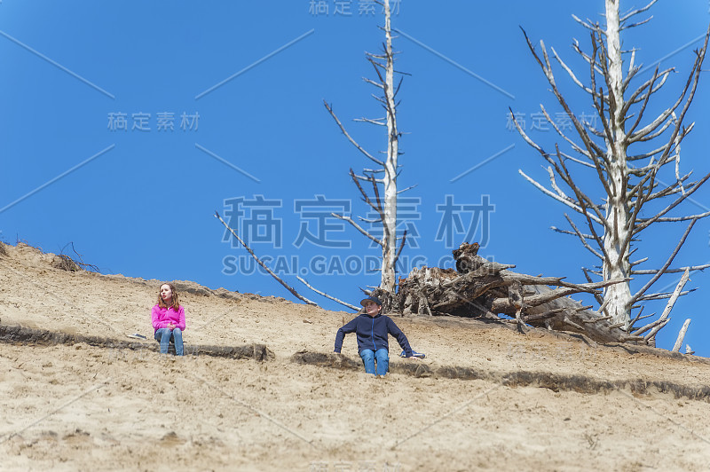 男孩和女孩爬上俄勒冈海岸的一个大沙丘后休息