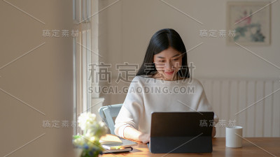 一个女孩在现代客厅里用数码平板电脑和咖啡杯