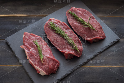 生肉，牛肉和迷迭香在黑色背景。三个项目