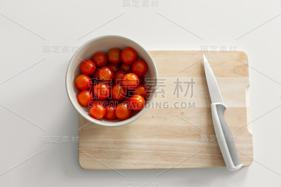 砧板上放一碗圣女果。烹饪健康美味的食物