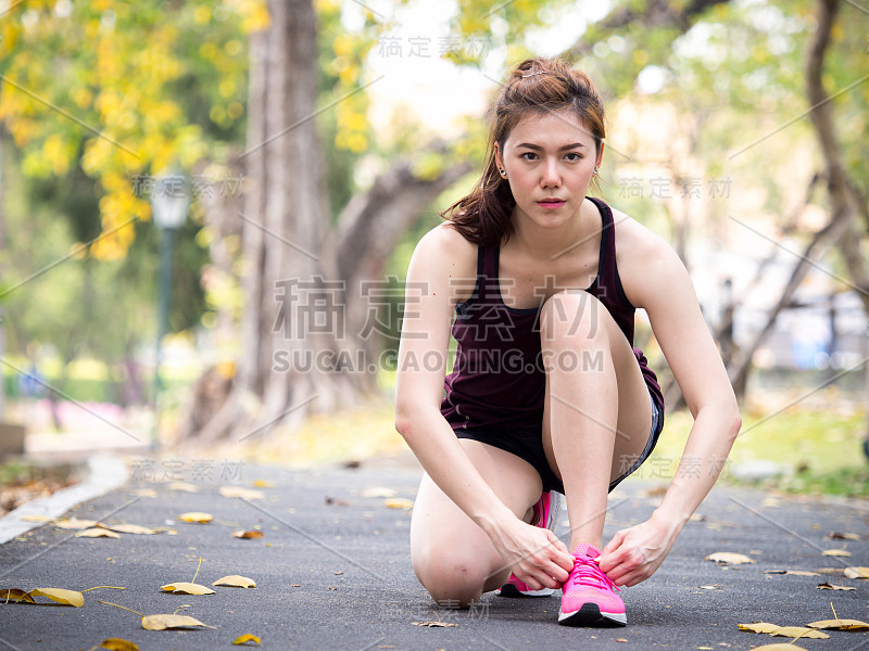 运动员年轻女子运动跑步收紧锁紧跑鞋/运动鞋在田径运动场，运动跑步和健康生活方式的概念