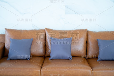 白色墙壁的棕色沙发上的灰色枕头。客厅内饰。