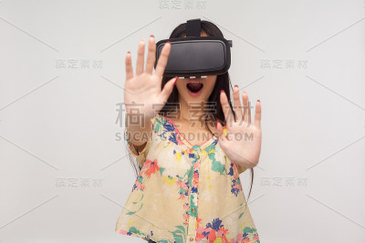 惊喜的女人戴着VR眼镜，举起手掌，玩电子游戏说哇