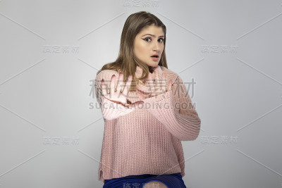 一个年轻女性的肖像穿着粉红色毛衣与停止手势