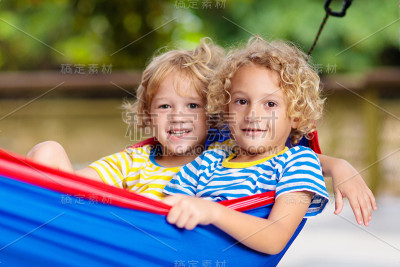 男孩在吊床。孩子们在夏天的花园里玩耍。