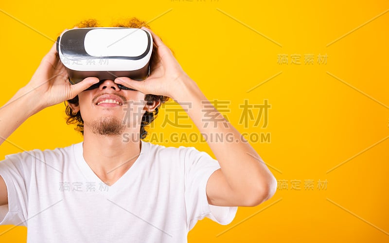 亚洲英俊的卷发男子他使用虚拟现实头盔或VR眼镜隔离