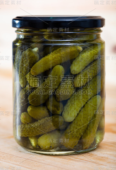 腌黄瓜与香料在玻璃罐中在一个木制表面