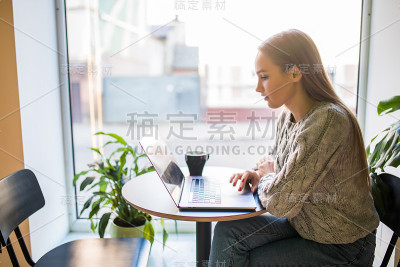美女在咖啡厅拿着笔记本电脑喝咖啡