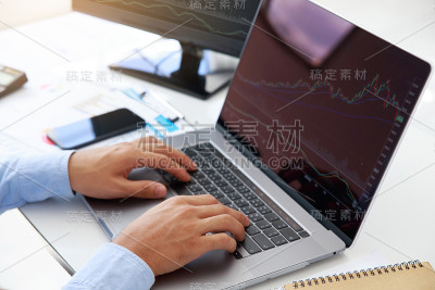 近距离观察年轻商人在笔记本电脑和办公室台式电脑上对股市金融指数的统计图表分析。分析和交易股票的概念。