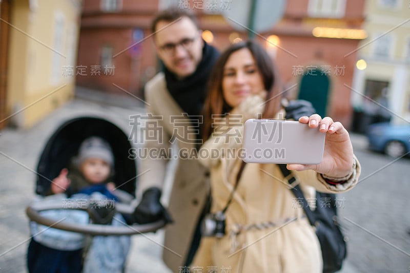 年轻的父亲和母亲与儿子在户外婴儿车