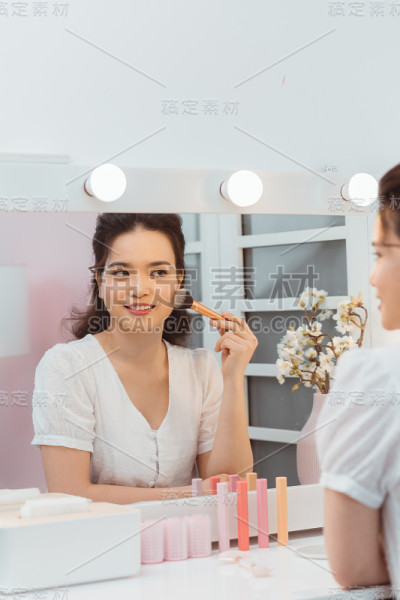 年轻漂亮的女人在镜子旁边化妆