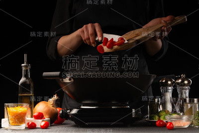 厨师烹饪说，意大利面食与肉和蔬菜，倒樱桃番茄，冷冻，在黑色的背景。横架，餐饮经营