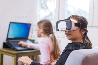 两个小女孩在用电脑和虚拟现实眼镜