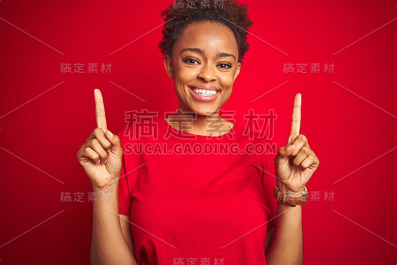 年轻美丽的非洲裔美国女人与非洲式的头发在孤立的红色背景微笑惊讶和惊讶，指着手指和举起的手臂。