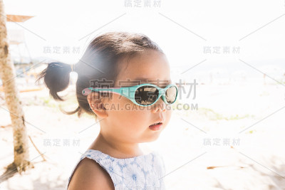 可爱的小女孩戴着眼镜在海滩上的肖像。