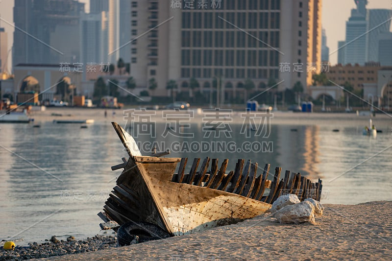 在平静的蓝色海水附近的海滩上，以多哈的城市景观为背景