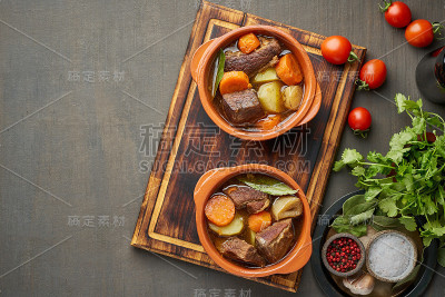 牛肉炖牛肉配大片的牛肉和蔬菜。深棕色的背景。俯视图，复制空间