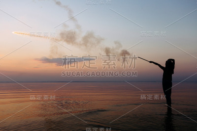 一个小女孩在日落时放烟花的剪影