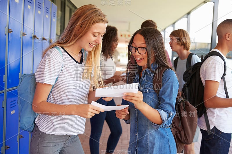 快乐的少女们在学校走廊里分享考试成绩