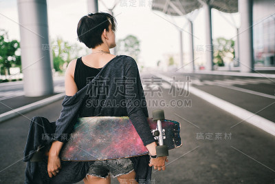 年轻的白人潮女人在街上玩着长板滑板