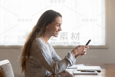 微笑的千禧女孩在家里使用现代智能手机