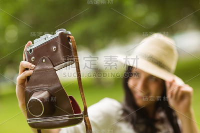 微笑的黑发女子在用复古相机自拍