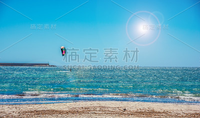 阳光照耀着阿尔盖罗海岸的风筝冲浪者