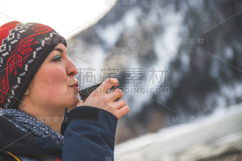 户外荒野探险:一个白人女孩正在喝着一杯金属茶