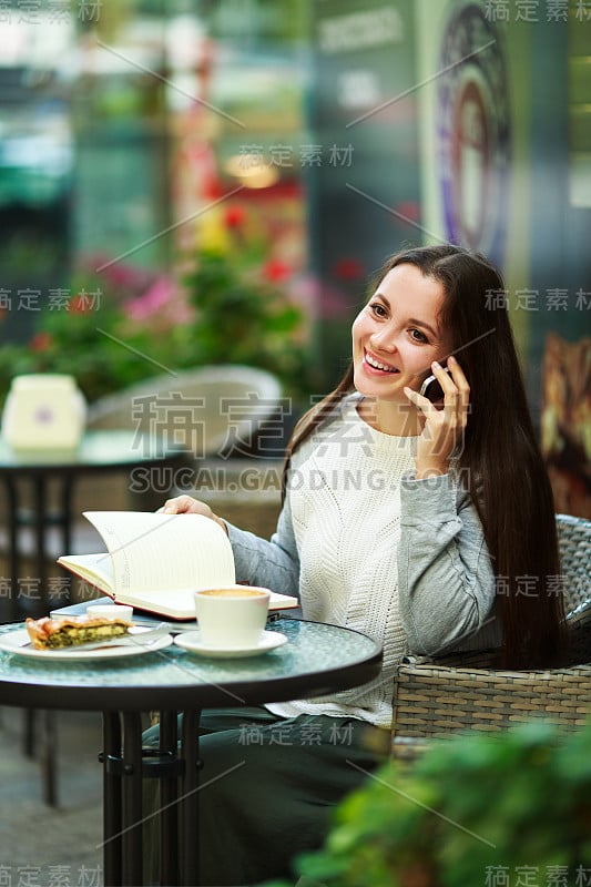 年轻的模特看着一个棕色长发的女人坐在咖啡厅里吃早午餐。白种女性唇妆自然，坐在咖啡厅的桌子上抬头看。商