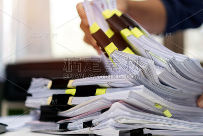 商人的手工作在成堆的文件，搜索信息的办公桌办公室，商业报告文件，成堆的未完成的文件实现与剪辑室内，业