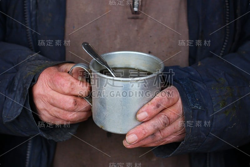 可怜的人拿着茶在冬天取暖。