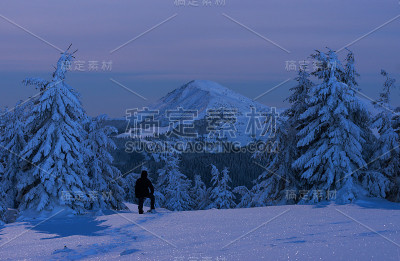 人们在暮色中欣赏冬山景色