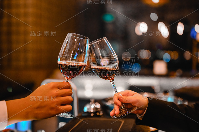 两位调酒师在日落时分的餐厅品酒活动中享用一杯酒。酒保，品酒，晚餐，葡萄酒，饮料，晚餐概念。