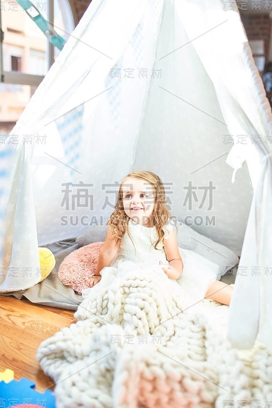 可爱的金发小孩坐在幼儿园里的毯子上玩
