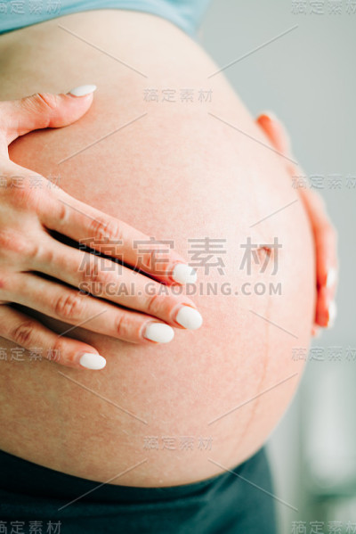 在演播室里，穿着运动服的怀孕女孩拥抱着她裸露的肚子
