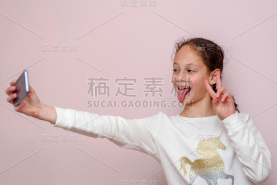 少女用粉色背景的手机自拍。