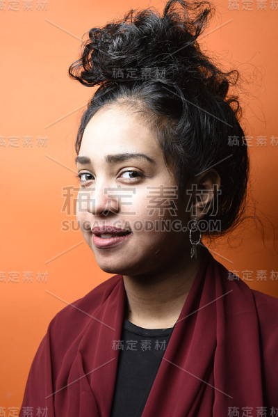 工作室拍摄的年轻美丽的埃及少女与黑色的头发与橙色的背景