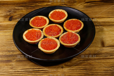 木桌上放着红鱼子酱馅饼