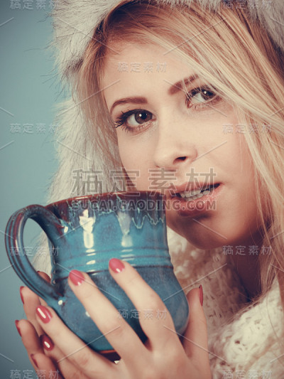 金发女人在冬天毛茸茸的帽子喝