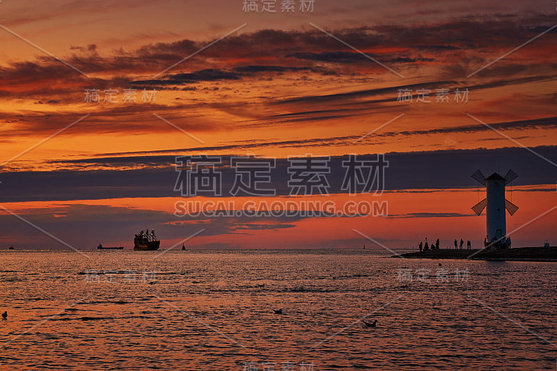 在波罗的海风车形状的灯塔上，夕阳和游客的剪影在Swinemünde。Swinoujscie、波兰