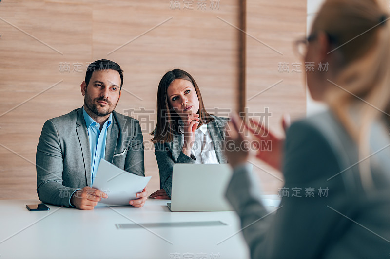 在一场工作面试中，细心的人力资源经理们在倾听一名女性的讲话。